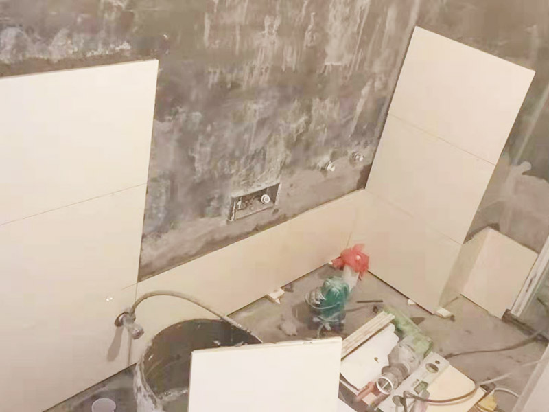 衛生間墻面貼磚：首先應除去基層表面的污垢，油漬，浮灰;除去基層上所有涂料層，膩子層;如果基層未能達到平整度要求，需對基層進行預先的找平處理。鋪貼瓷磚前需事先找好垂直線，以此為基準鋪貼的瓷磚高低均勻、垂直美觀;此外，施工前在墻體四周需彈出標高控制線，在地面彈出十字線，以控制地磚分隔尺寸。對瓷磚的色彩、紋理、表面平整等進行嚴格的挑選，然后按照圖紙要求預鋪。對可能出現的尺寸、色彩、紋理誤差等進行調整、交換，直至達到最佳效果。 調制粘結劑：加水后將粘結劑漿料攪拌至潤滑均勻，無明顯塊狀或糊狀結塊，攪拌后的漿料靜置5-10分鐘后再稍加攪拌1-2分鐘即可使用。 將瓷磚平整地鋪貼在基層上，使用橡膠錘將瓷磚拍實鋪平。施工過程中，可小幅度轉動瓷磚，使漿料與瓷磚背面充分接觸。